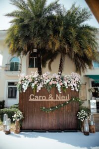 Charming outdoor wedding setup with floral decorations and personalized signage for a stunning event backdrop.